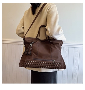 Macro shot of large coffee brown tote bag with metal rivets and decorative side tassels