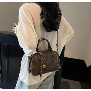 Detail of vintage dark brown Boston bag with marble texture and braided pendant
