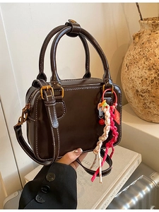 Deep brown Boston bag with contrast white stitching and colorful woven rope charm