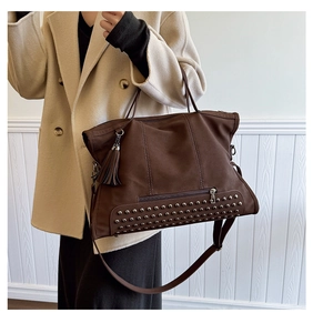 Detail of dark brown tote bag with silver metal rivets and detachable leather tassel charms