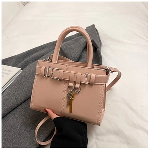 Detail of a pink square handbag featuring a decorative buckle and metal key pendant