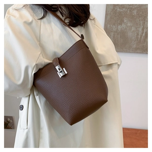 Detail of dark brown lychee leather bucket bag with silver buckle worn on a beige coat