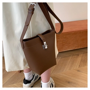 Deep brown lychee grain leather bucket bag shown as a crossbody on a casual white dress