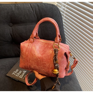 Close-up of pink Boston bag with vintage pleated texture and embossed lettering