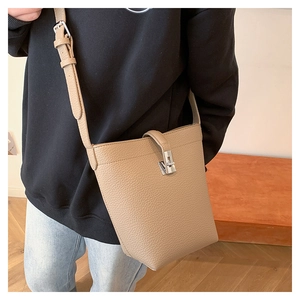 Detail of khaki leather bucket bag showing lychee texture and silver metal twist lock