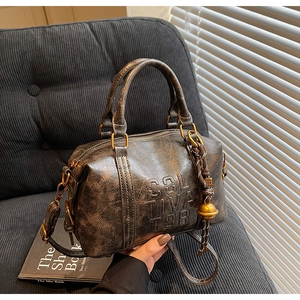 Detail of vintage bronze Boston bag with distressed leather texture and embossed logo