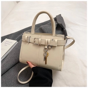 Detail of cream PU leather handbag with metal buckle strap and key-shaped charm