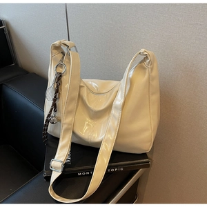 Detail of cream glossy tote bag featuring silver hardware and a tennis racket charm