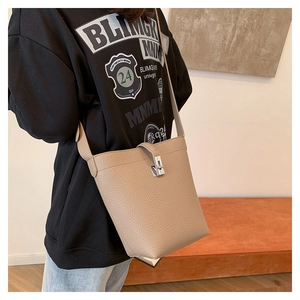 Detail of lychee pattern bucket bag with silver metal swivel lock on a crossbody strap