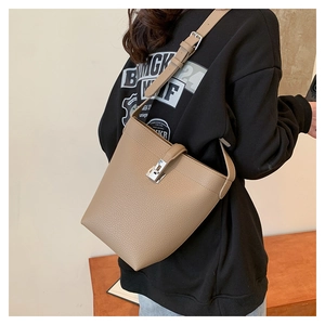 Detail view of khaki litchi grain bucket bag featuring a silver metal twist lock closure