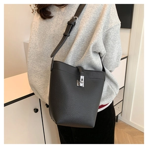 Close-up of litchi-pattern leather bucket bag featuring a silver metal twist lock detail