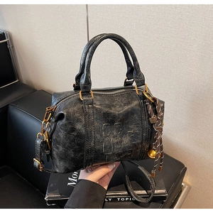 Detailed close-up of retro black Boston bag with cracked leather and woven knot charm