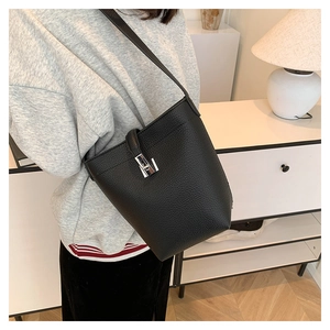 Detail of black lychee grain leather bucket bag featuring a silver twist lock closure
