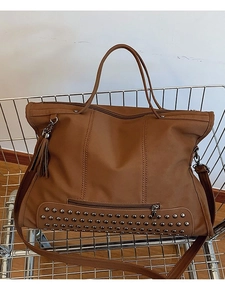 Retro brown oversized tote bag with metal studs and tassel in a metal shopping cart