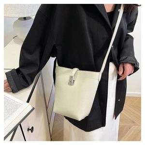 Detail of cream lychee leather bucket bag with silver turn-lock and fine stitching