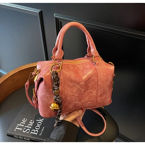 Detail of dusty rose Boston bag featuring textured faux leather and bell charm