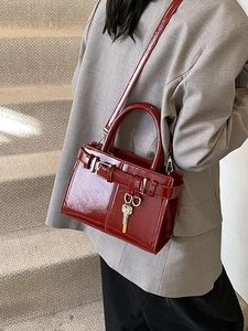 Elegant burgundy glossy leather tote bag with metallic key charm and belt strap detail