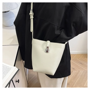 Detailed view of cream-white lychee texture bucket bag worn by a model in soft lighting
