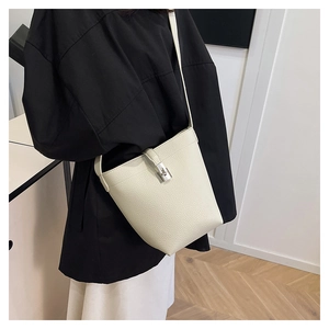 Close-up of beige lychee pattern bucket bag with silver metal twist lock on shoulder