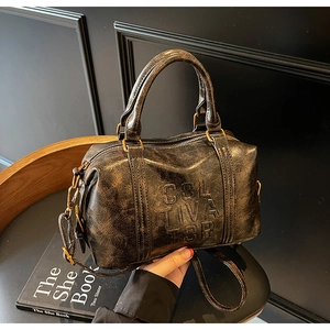Detail showing vintage Boston bag texture with embossed logo and retro bronze hardware