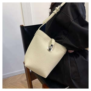 Close-up of cream white lychee grain bucket bag with silver buckle on a model