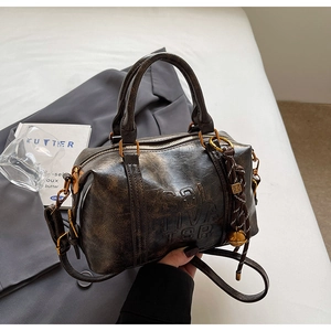 Detailed close-up of dark brown vintage Boston bag with embossed logo and woven charm