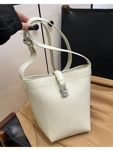 Minimalist beige lychee grain leather bucket bag with silver metal buckle closure and strap
