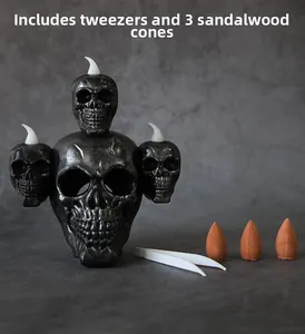 Detail view of gothic skull backflow incense burner with sandalwood cones and tweezers