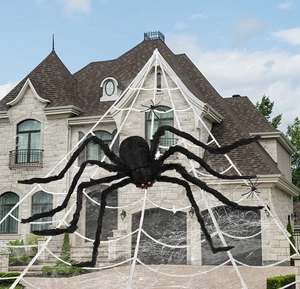 Outdoor Halloween decoration with giant plush spider and large white web on house