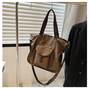 Detail of dark brown nylon tote bag with metal chain accent hanging on hanger