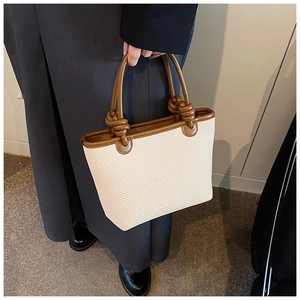 Détail du sac cabas tissé crème avec bandoulières en cuir marron et détails de nœuds