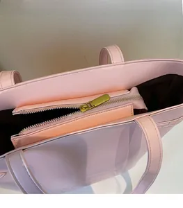 Detail of pink leather tote bag showing smooth gold metal zipper and dark brown lining