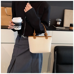 Détail rapproché du sac tissé avec poignées en cuir marron et détails de nœuds