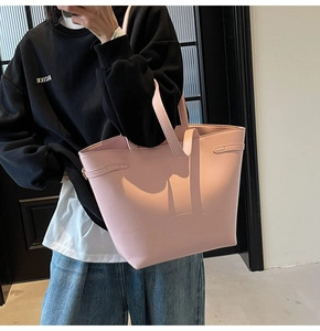Detail view of pink leather tote bag with embossed logo and adjustable side straps