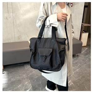 Side view of large black waterproof nylon tote bag with metal chain detail on model