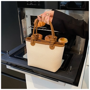 Détail du sac seau tissé avec poignée nouée marron et texture contrastée crème