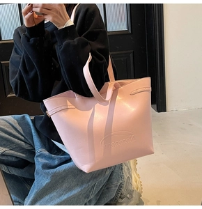 Close-up of pink tote bag showing the embossed brand logo and side buckle detail