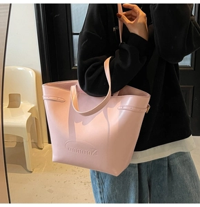 Detail view of pink leather tote bag featuring debossed NotomoRo logo and side buckles