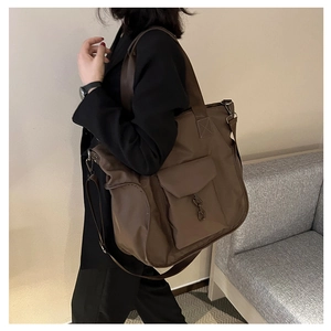 Detail of dark brown large tote bag with front flap pocket and metal hook buckle