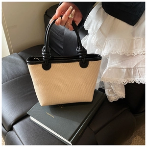 Détail du sac cabas tissé minimaliste avec poignées en cuir noué sur un siège