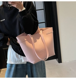 Detail of pink faux leather tote bag showing golden hardware and embossed logo on front