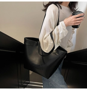 Detail of a black large-capacity tote bag with Nevermind embossing on smooth PU leather
