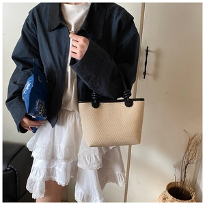 Détail du sac cabas en paille avec bordure en cuir noir et texture en fibres tissées