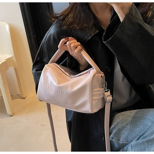 Polished lavender cylinder bag shown on a model highlighting its high gloss finish and strap