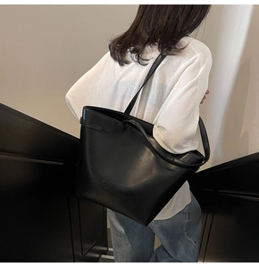 Detailed view of the embossed logo and glossy leather texture on a black tote bag