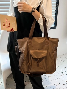 Brown large capacity nylon tote bag shown on model with front pocket and shoulder strap