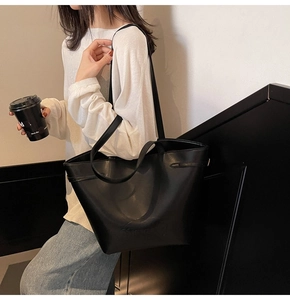 Detail of a black matte PU leather large tote bag with stylish metal buckle on shoulder strap