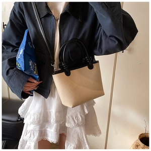 Vue détaillée du mini sac cabas en paille avec bordure en cuir noir porté en bandoulière