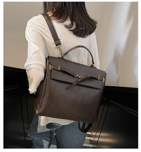 Deep brown large capacity handbag showing back carrying style on a model in a minimal room