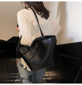 Macro detail of the embossed Naimiro logo on a high-quality black leather bucket bag